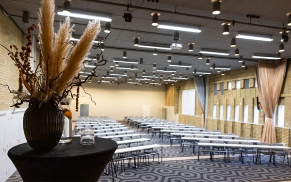 Större möteslokal med uppställda bord och stolar i klassrumsstil.