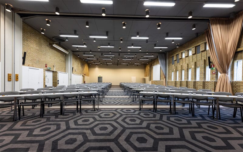 Större möteslokal med uppställda bord och stolar i klassrumsstil.