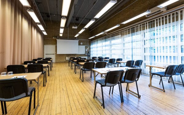 Större möteslokal med uppställda bord och stolar i klassrumsstil.