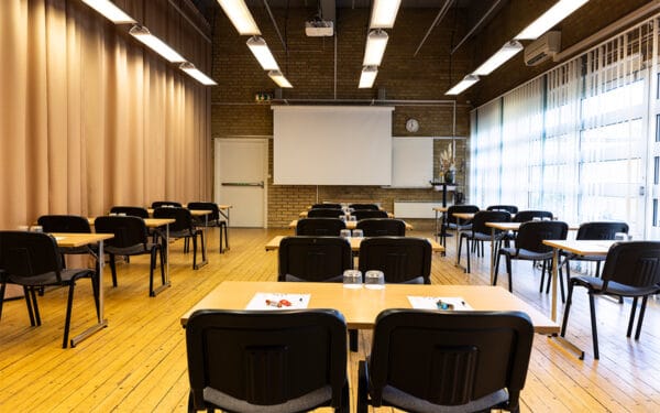 Större möteslokal med uppställda bord och stolar i klassrumsstil.