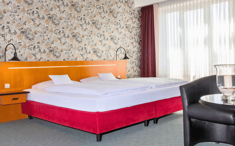 Hotelzimmer mit einem Doppelbett, einem Sessel und einem Tisch