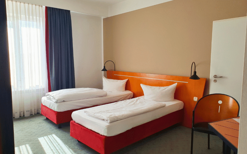 Hotelzimmer mit zwei Einzelbetten, einem Schreibtisch und einem Stuhl