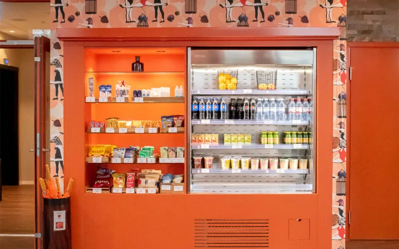 Hotellshop med kylda drycker och snacks i hylla och kyl