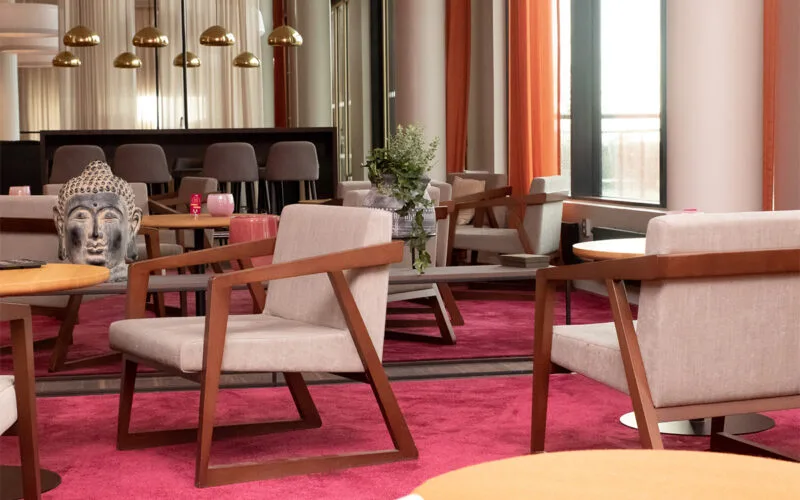 Hotellobby med moderna fåtöljer, rosa matta och stora fönster