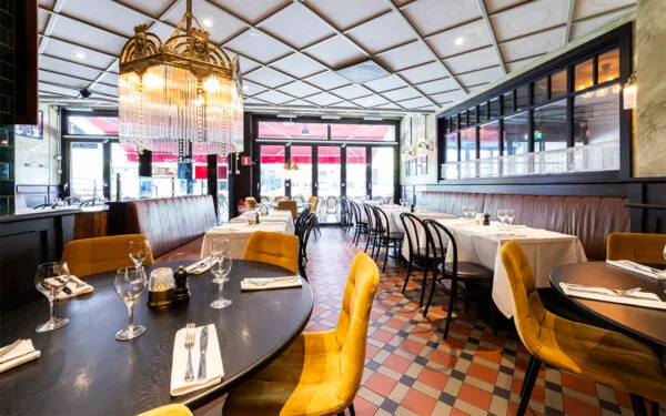 Restaurangsal med dukade bord och vita dukar.