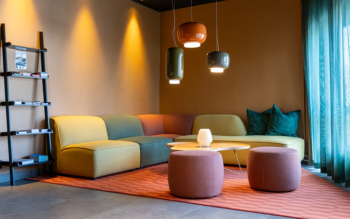 Lounge with colorful corner sofa, round poufs and modern ceiling lights