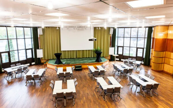 Mötesrum Salongen på ProfilHotels Nacka med scen, projektorduk och uppställda konferensbord.