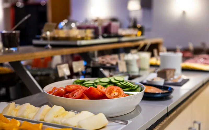 Närbild på fräscha grönsaker som tomater och gurka på hotellfrukostbuffé