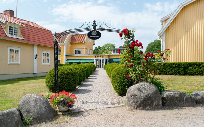Entrégång med blommor och skylt.