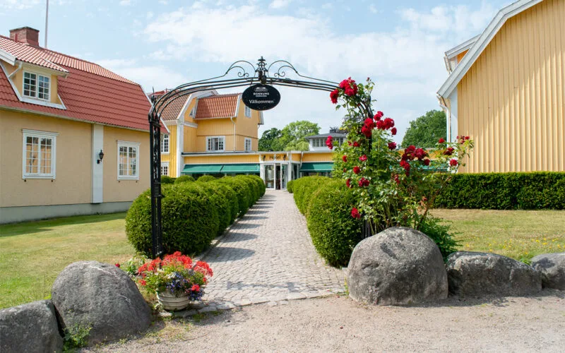 Entrégång med blommor och skylt.