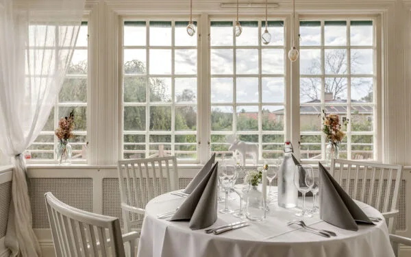 Dukat bord vid stora fönster med utsikt mot grönska.