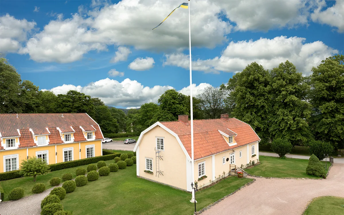 Gule palæbygninger med tegltage og frodige grønne omgivelser.