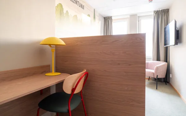 Enkelrum med skrivbord och stol, med gul lampa.