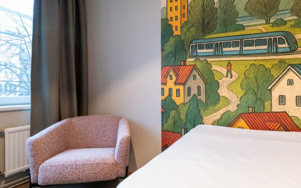 Singelrum med säng och fotölj med fin tapet i på väggen