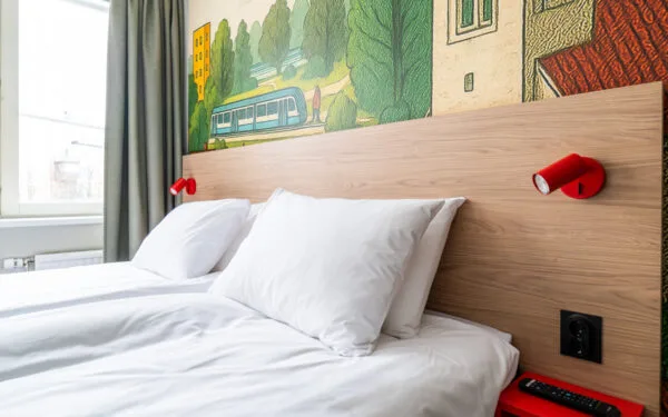 Rum med säng, sängbord, sänglampa, tapet som är mönstrad och bäddsoffa.