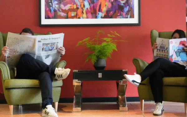 Zwei Gäste sitzen in der Hotel-Lobby und lesen entspannt Zeitung.