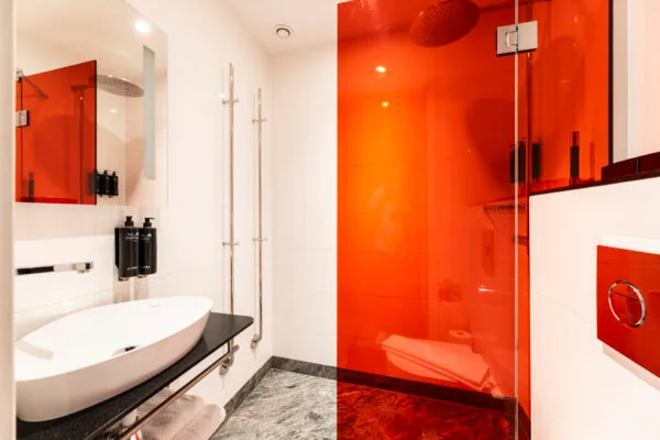 Badrum med dusch i rött glas, modernt handfat och spegel