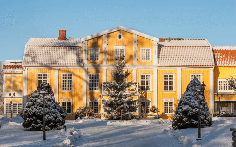 Ronnums Herrgård täckt i krispig vit snö med en stor gran placerad framför entren.
