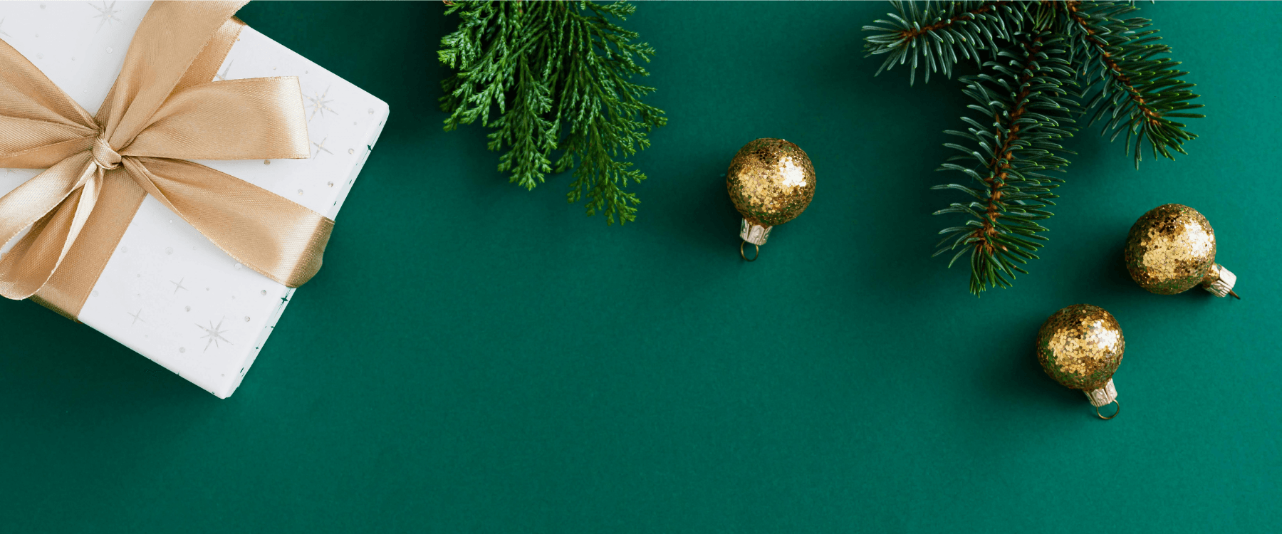 Julklapp och julgranskulor på en grön bakgrund.