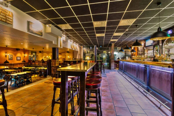 Lång bardisk med höga stolar i en traditionell pubmiljö.