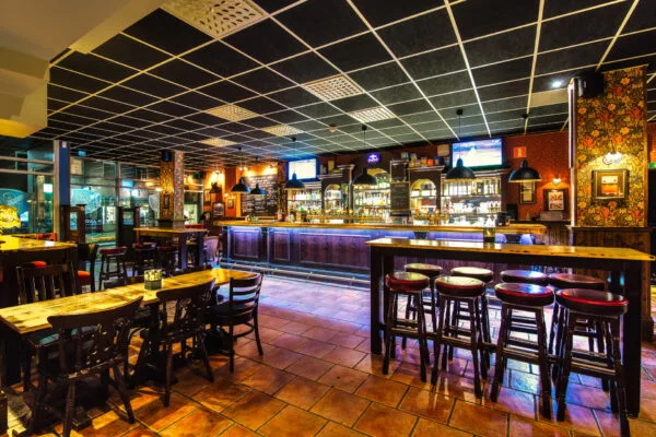 Pubmiljö med höga bord och stolar i en varm belysning.