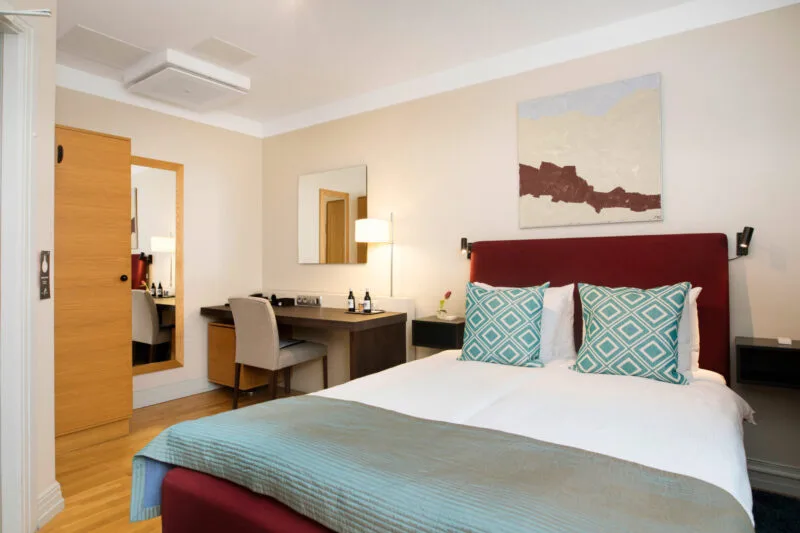 Dubbelrum med säng, fåtölj och bord.