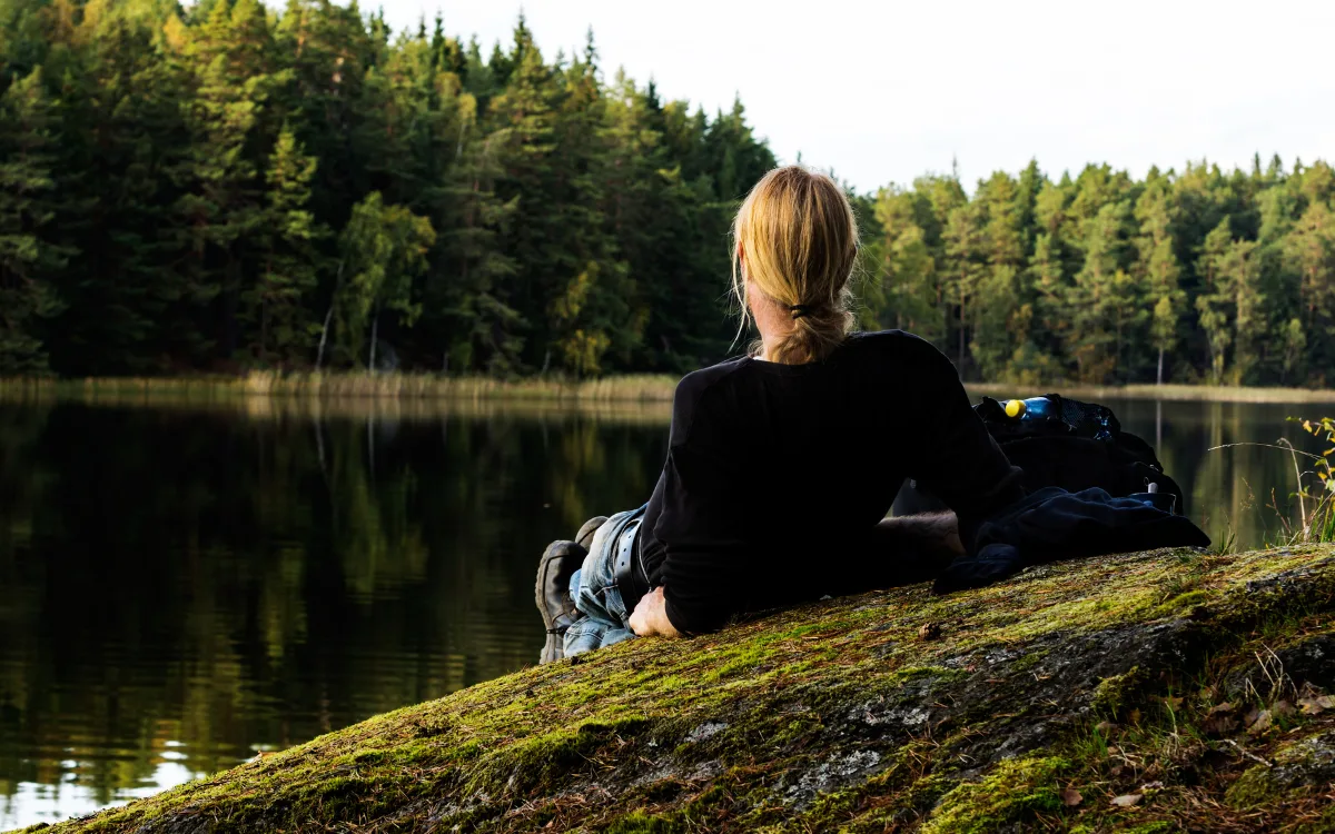 Person sitter på klippa vid sjö och njuter av utsikten