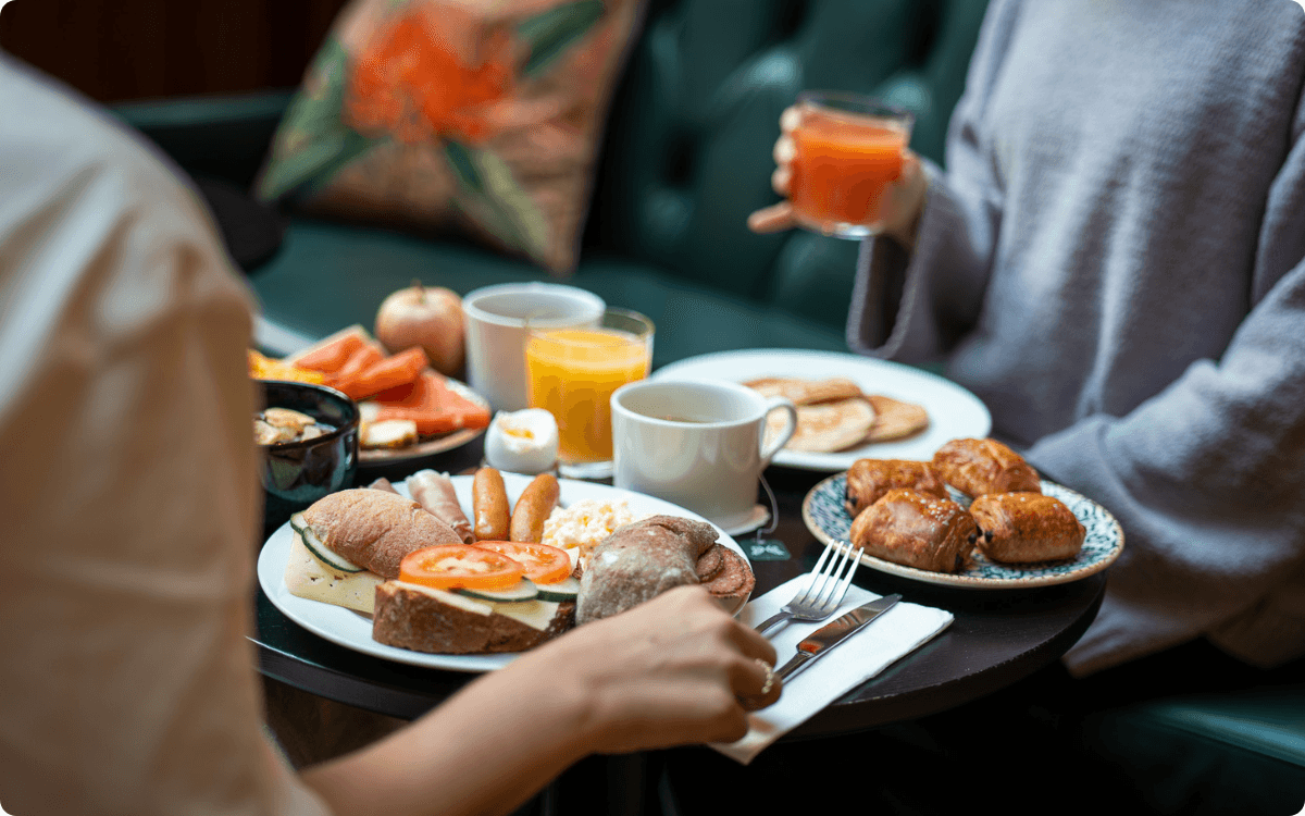 Frukostbord med kaffe, juice, smörgås, äggröra, pannkakor och mycket mer.