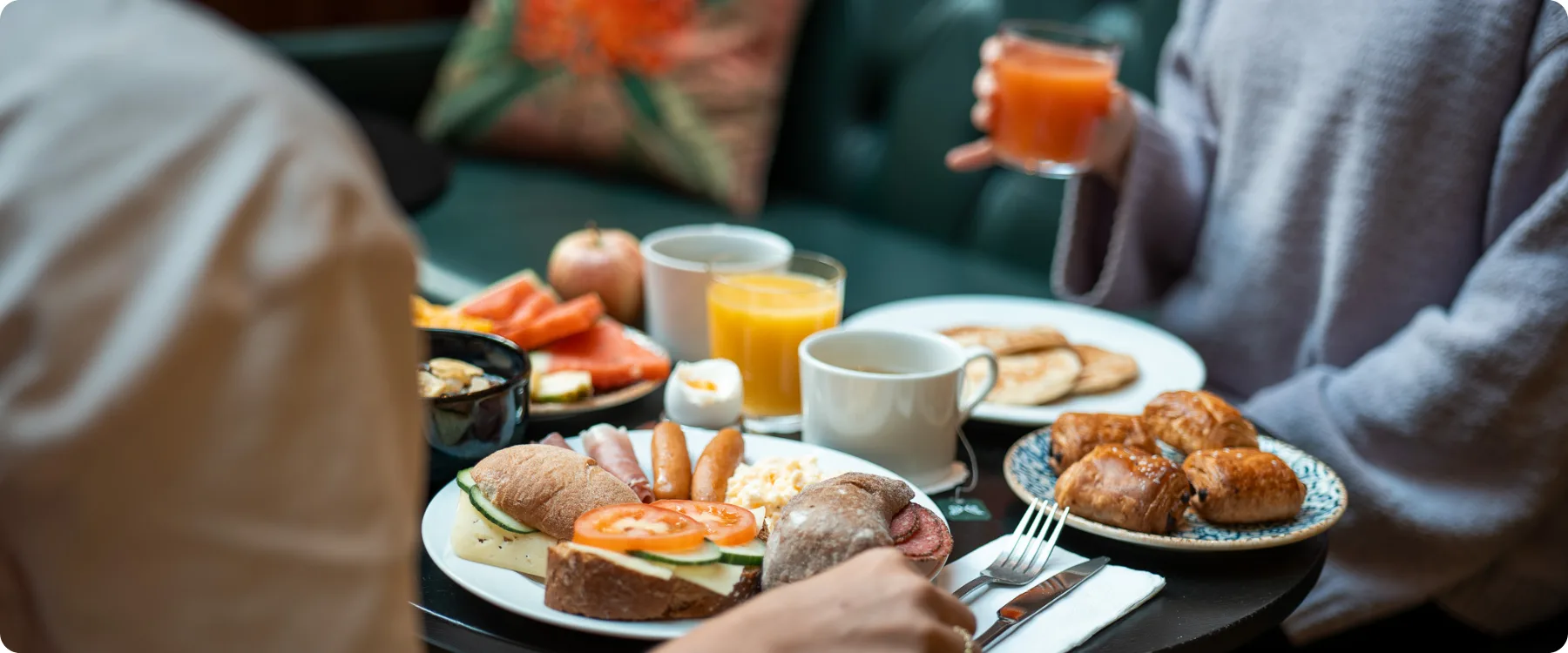 Frukostbord med kaffe, juice, smörgås, äggröra, pannkakor och mycket mer.