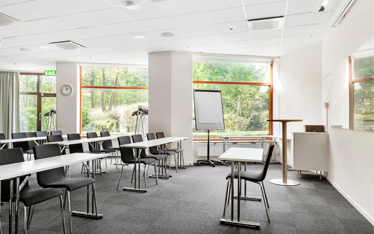 Ett ljust mötesrum med stora fönster med grönska utanför.