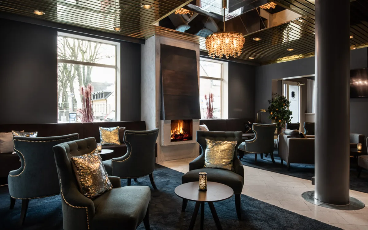 En hotell lobby inredd med mörka färger, takkrona, sammetsfåtljer och högt i tak.