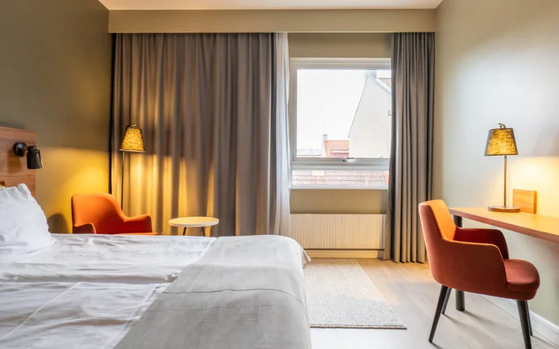 Mysigt hotellrum på ProfilHotels Grand Kristianstad med skrivbord, fotölj och tv på väggen