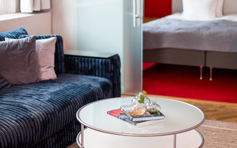 Sviten på ProfilHotels President som är inredd med blå soffa, soffbord och glasdörrar som leder in till sovrummet.