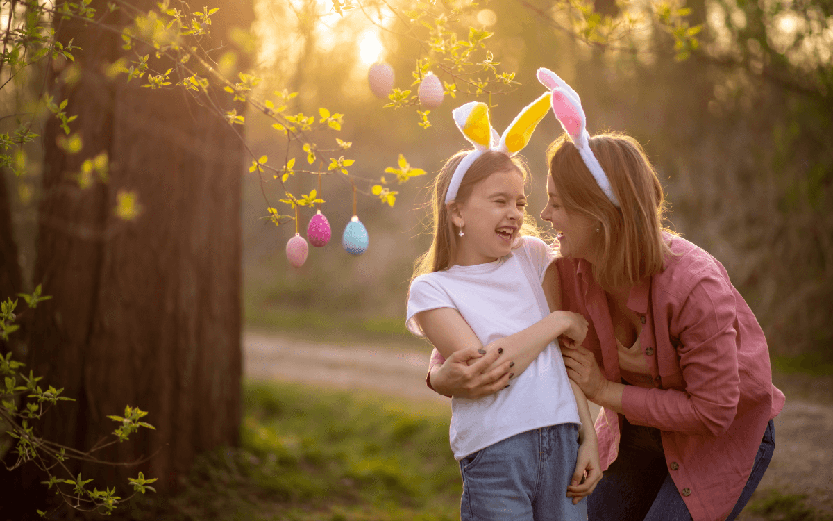 En mamma och en dotter håller om varandra iklädda diadem med kaninöron.