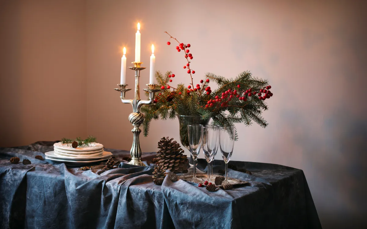 Table decorated with candles, glases, pine cones and pine tree twigs