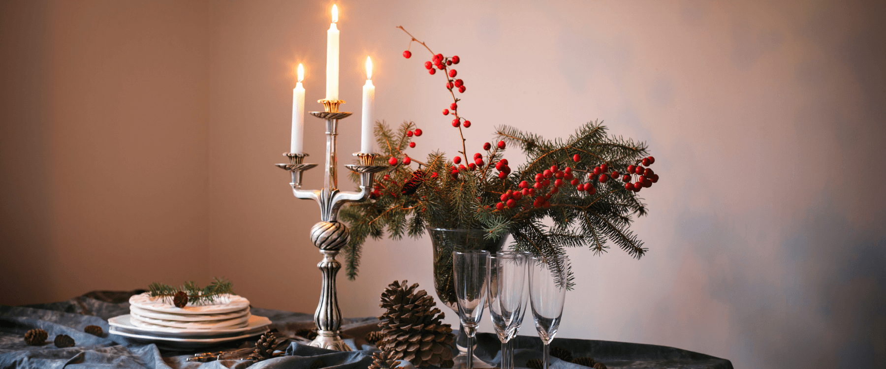 Decorated table with Candles, glases, pine cones and pine tree twigs.
