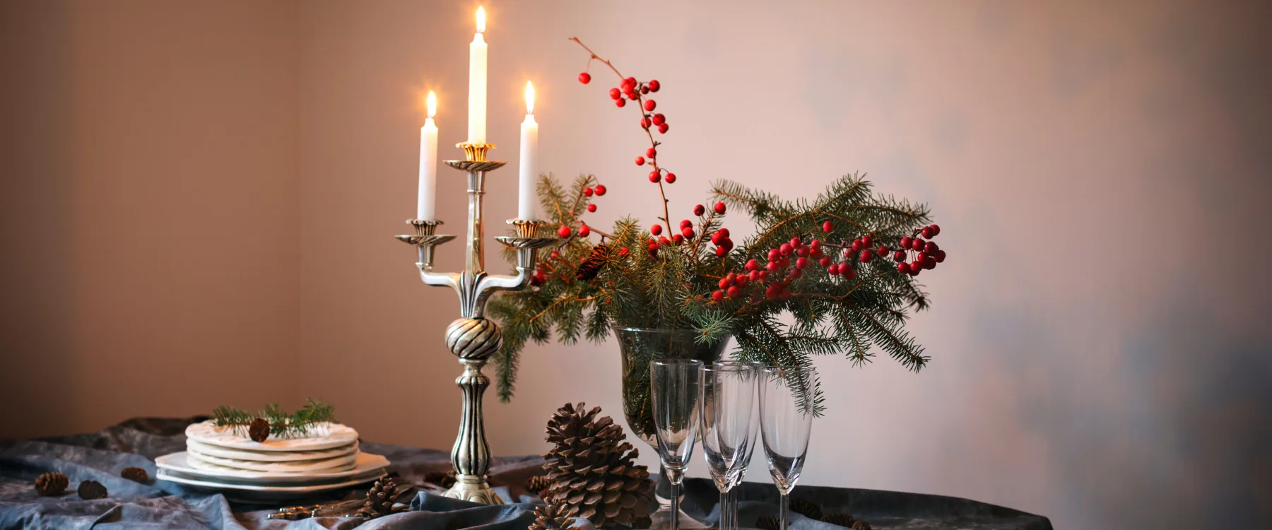 Decorated table with Candles, glases, pine cones and pine tree twigs.
