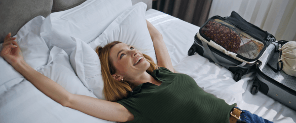 Frau im Hotelbett mit Koffer